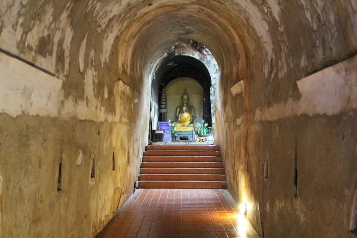 Golden Buddha statue at the end of an ancient stone tunnel