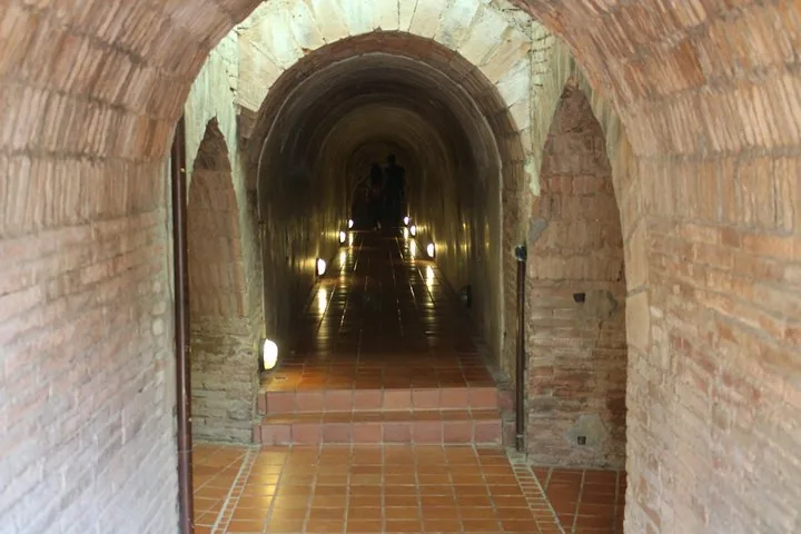 Brick tunnel with floor lighting and people walking in the distance
