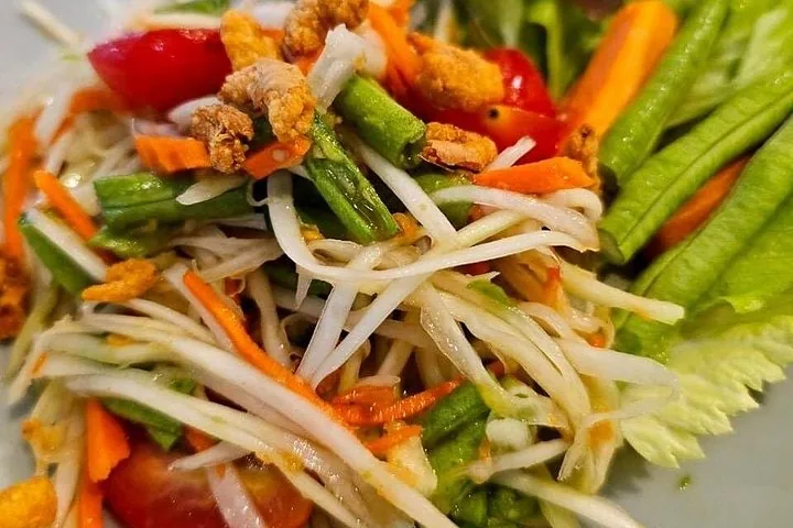 Close-up of green papaya salad with green beans and tomatoes.
